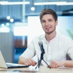 Business coach in office records online book, portrait looks at camera smiling