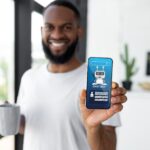 Cheerful black guy showing phone with chatbot screen