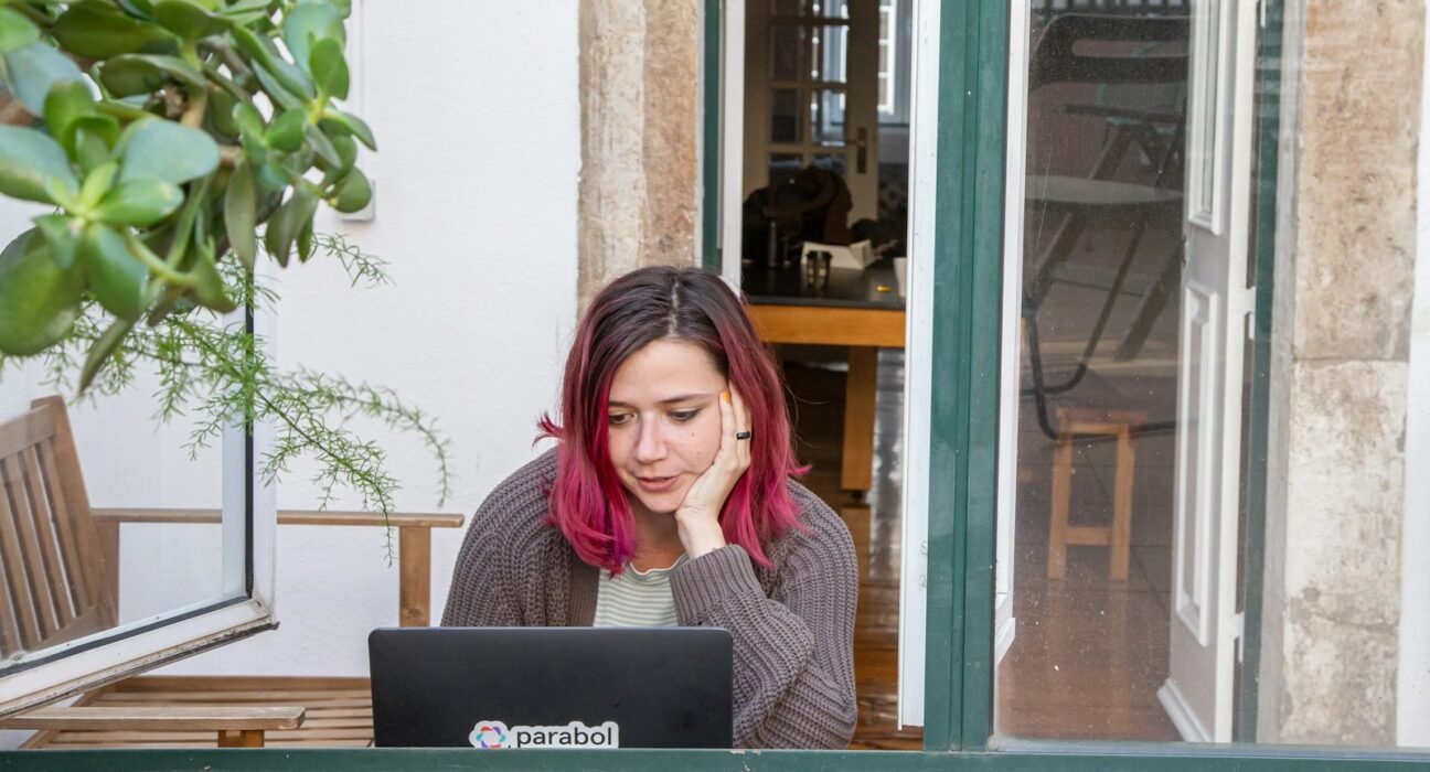 a woman with pink hair is looking at a laptop