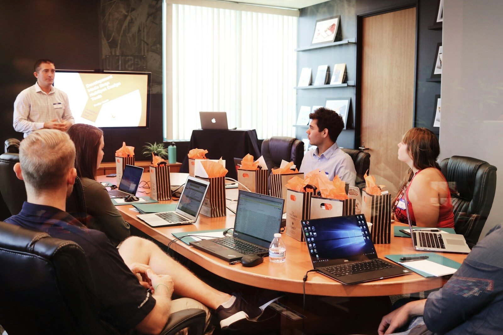 Coaching Business man standing in front of people sitting beside table with laptop computers